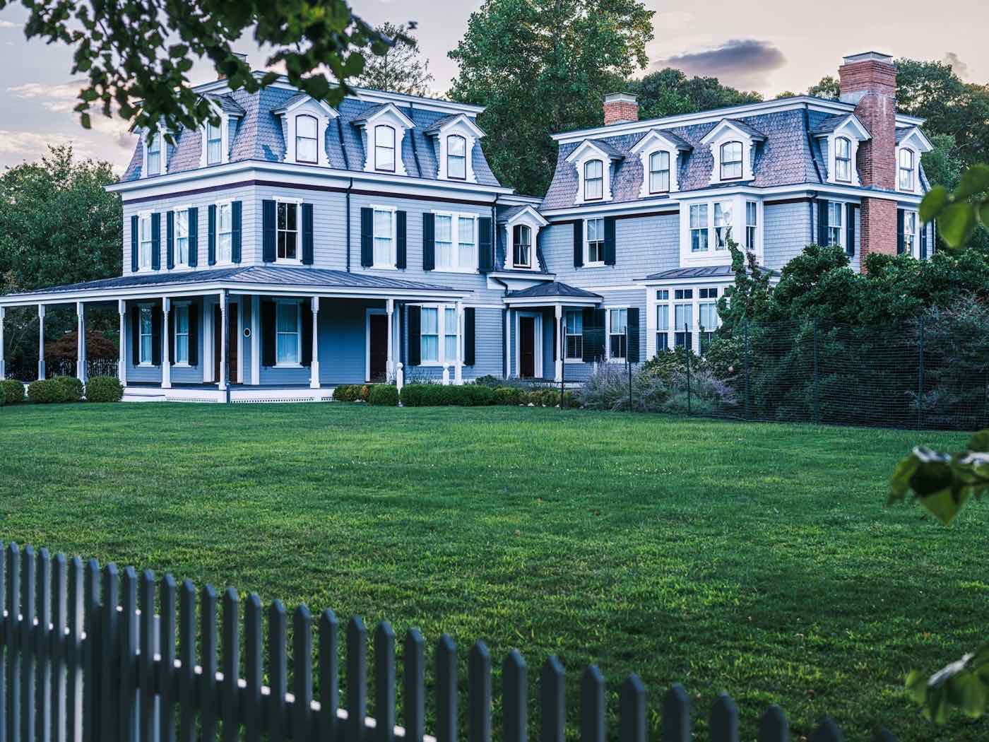 Historic Second Empire estate behind a deep front lawn at dusk